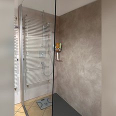 Die Dusche zeigt eine klare Glasabtrennung, einen Handtuchwärmer und eine praktische Ablage für Duschgel und Shampoo.