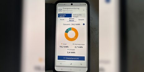 Ein Smartphone zeigt die Energiedaten einer Wärmepumpe mit einem Gesamtverbrauch von 24,3 kWh für den Monat an.