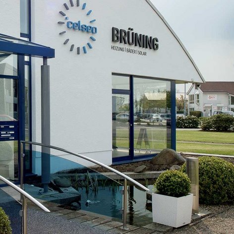 Das Gebäude hat eine klare, moderne Architektur mit einem auffälligen Logo und einem transparenten Vordach über dem Eingang.